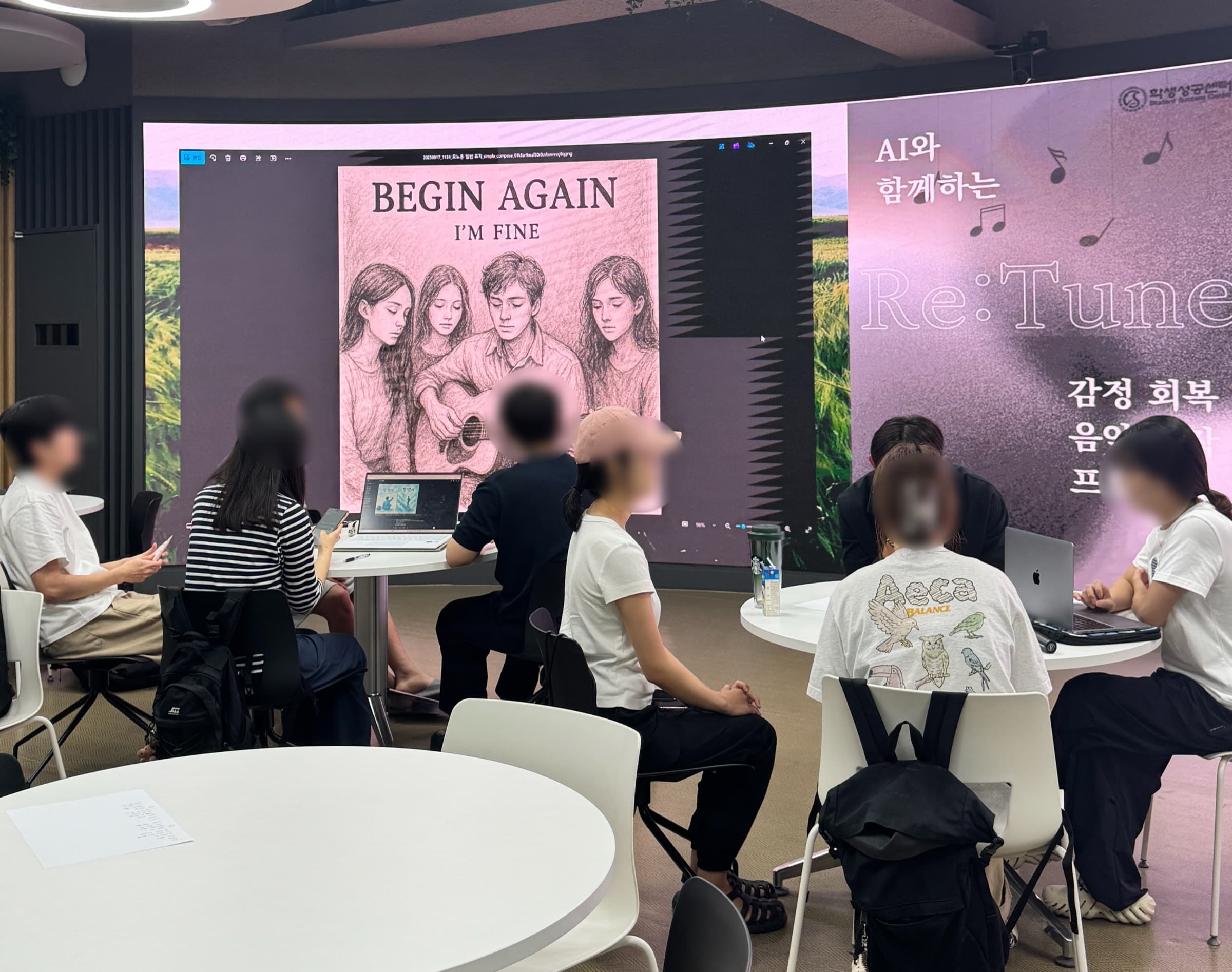 참여팀이 완성한 앨범 커버 ‘Begin again — I'm fine’이 큰 화면에 띄워진 가운데, 학생들이 둘러앉아 화면을 함께 보는 모습 (얼굴 비공개 처리)