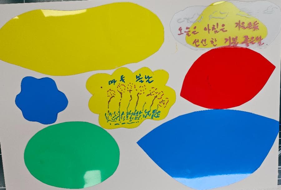 노랑·빨강·파랑·초록 색 필름 조각을 꽃과 나무, 구름 모양으로 오려 배치하고 그 위에 짧은 문장을 적은 작품
